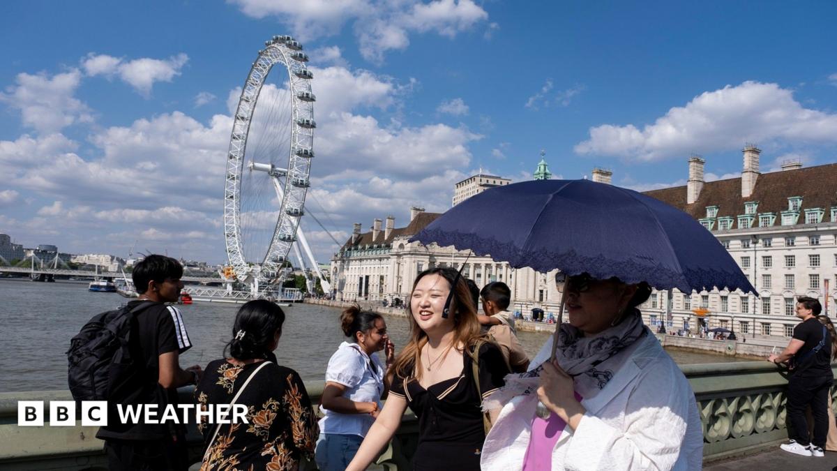 People walk on a bridge over the Thames in London using an umbrella for shade with strong sunshine overhead.