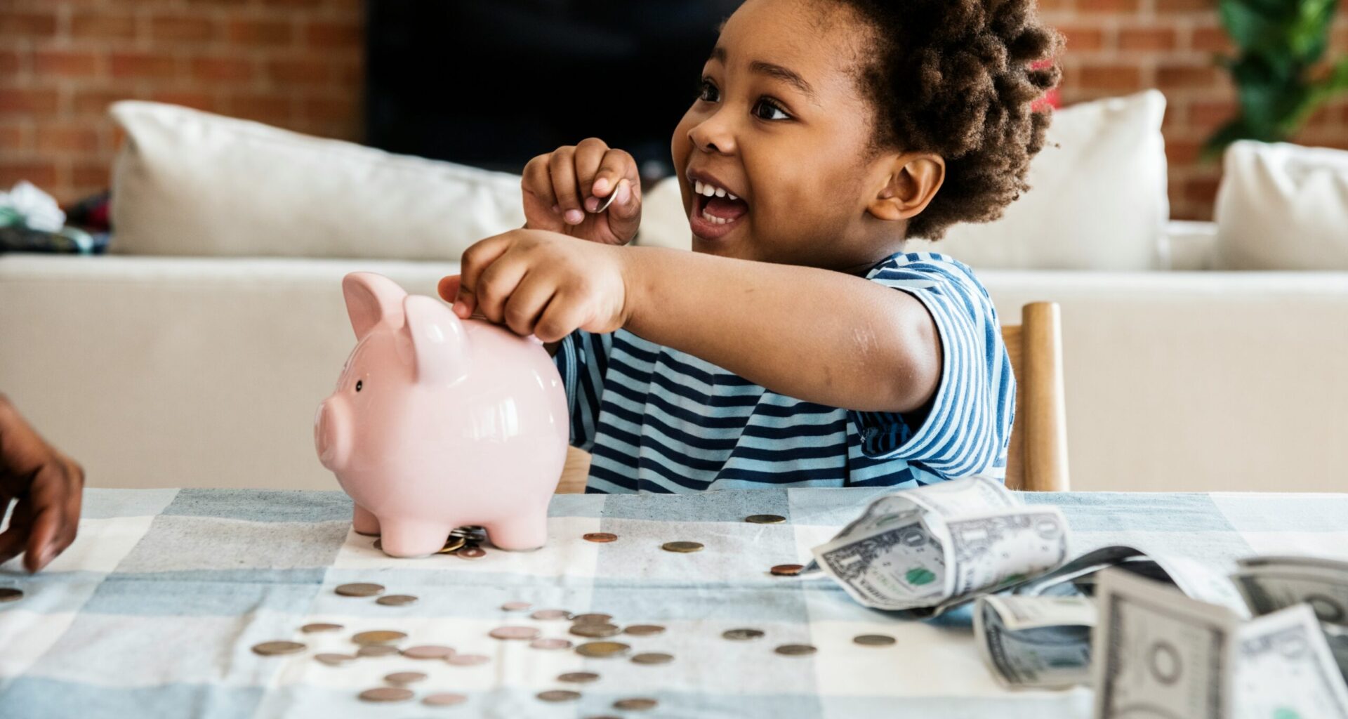Photo of a young child putting money into a piggybank.