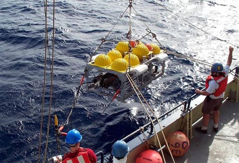 An Ocean Bottom Seismometer being lowered from a vessel into the water.