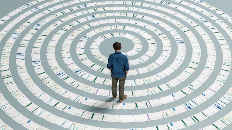 A man standing looking down on a line of different papers arranged in a spiral shape.