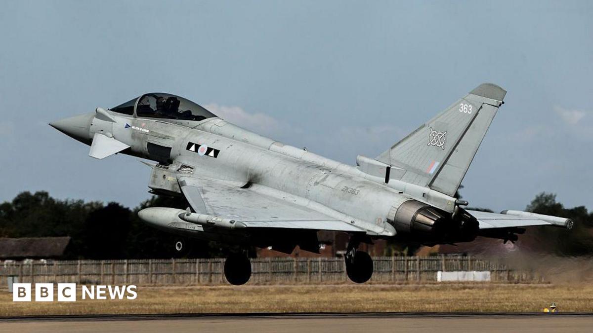 A grey Typhoon jet takes off on a runway with streams coming out of its exhaust.