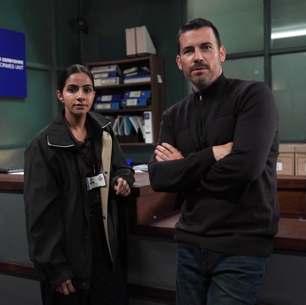 two people standing in a police office with a greater derbyshire major crimes unit sign. two people standing in a police office with a greater derbyshire major crimes unit sign.