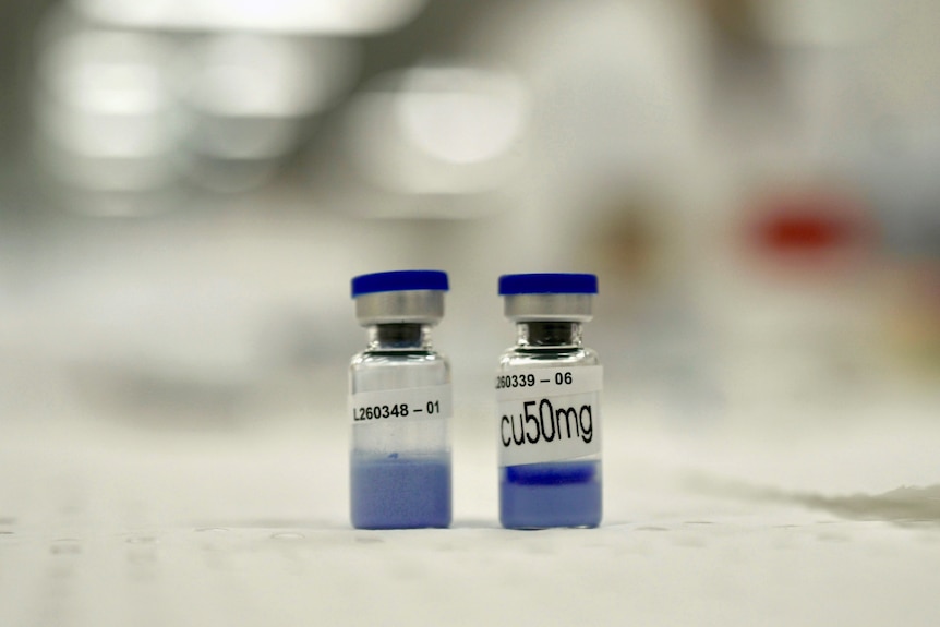Two small vials sitting on a surface. Both have very blue liquid in them.