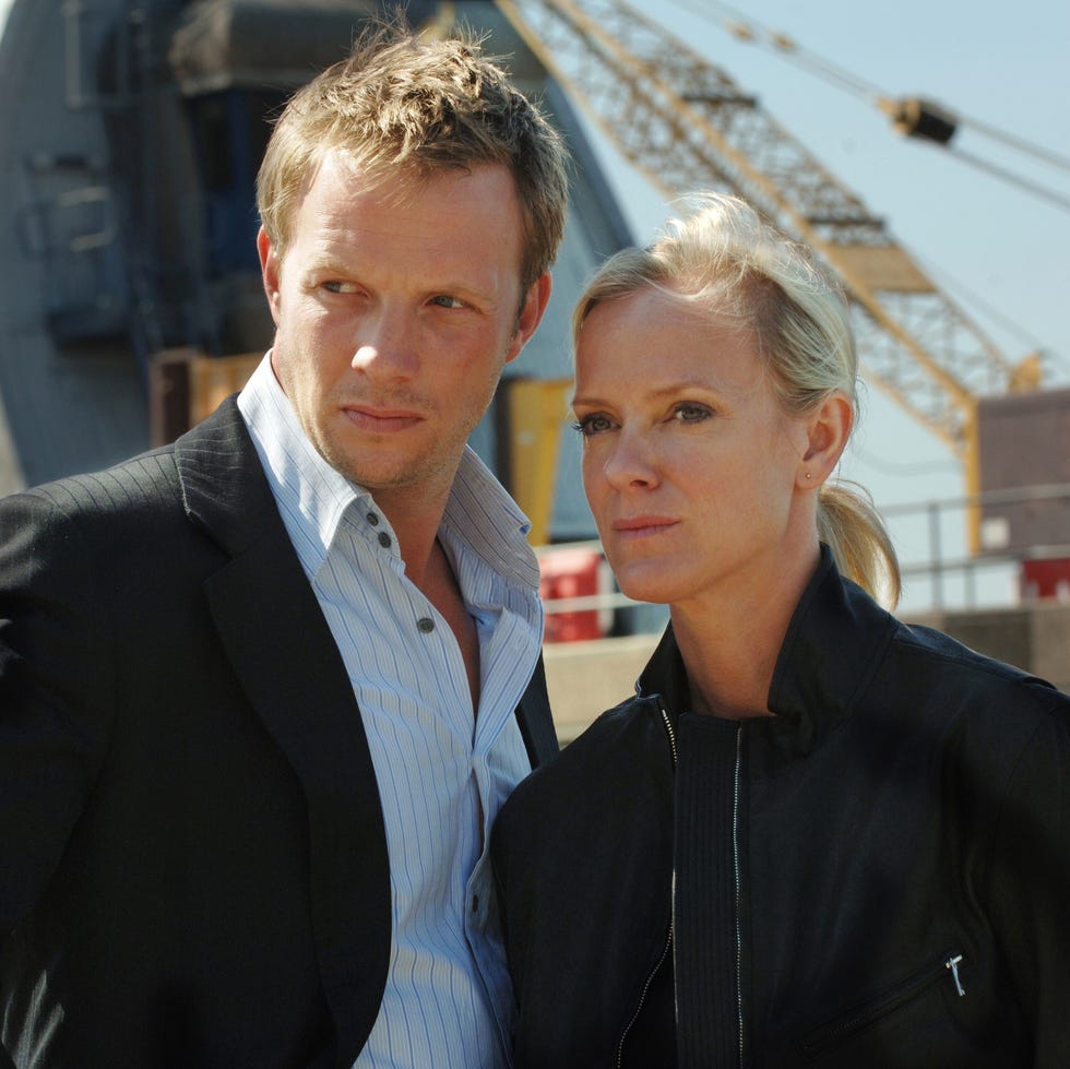 two people standing outdoors with a dome and cranes in the background. two people standing outdoors with a dome and cranes in the background.