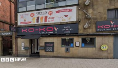 Street view image of the Ko-Ko Lounge, a stone building with two small square windows to the right of the entrance which is under a black canopy and a bright pink on black sign saying Ko-Ko Lounge