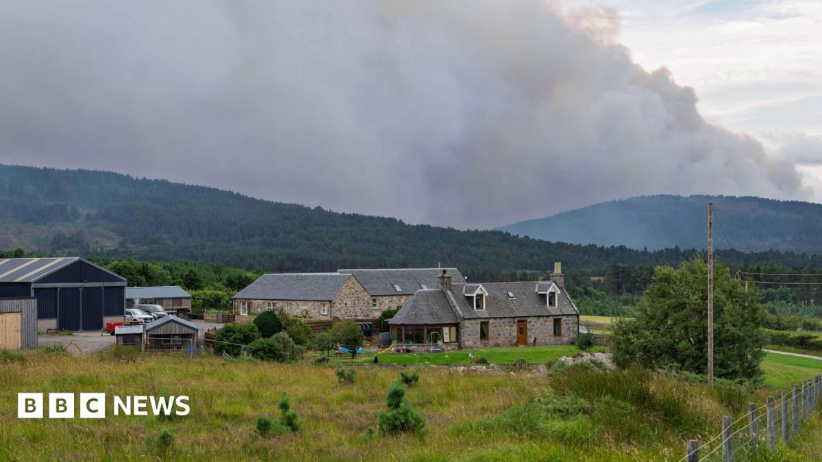 smoke over hills beyond farm buildings