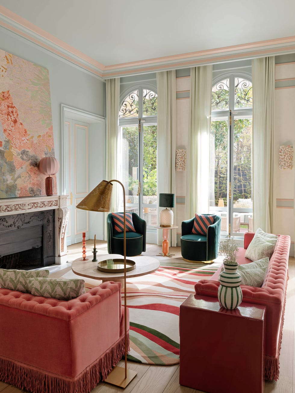 Bright and colorful living room with a modern aesthetic, featuring plush seating, decorative rug, and large windows.