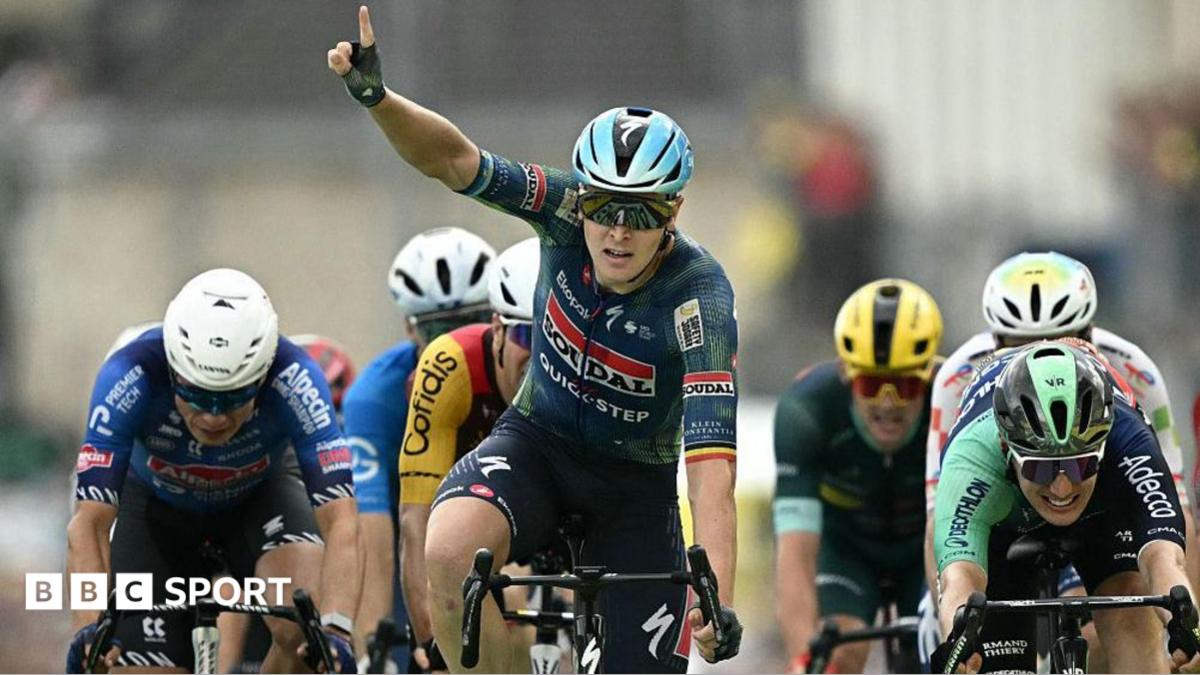 Tim Merlier celebrates winning stage 12 by raising a finger into the air