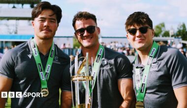 Three Worcester Warriors players celebrate winning the Champ Rugby title with the middle player Will Trewin holding the trophy