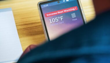 a top-down view of a smartphone over a person's shoulders. the phone says Extreme Heat Warning, 105 degrees F