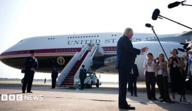 Trump stands in front of Qatari-gifted Air Force One and speaks to reporters who are holding boom microphones