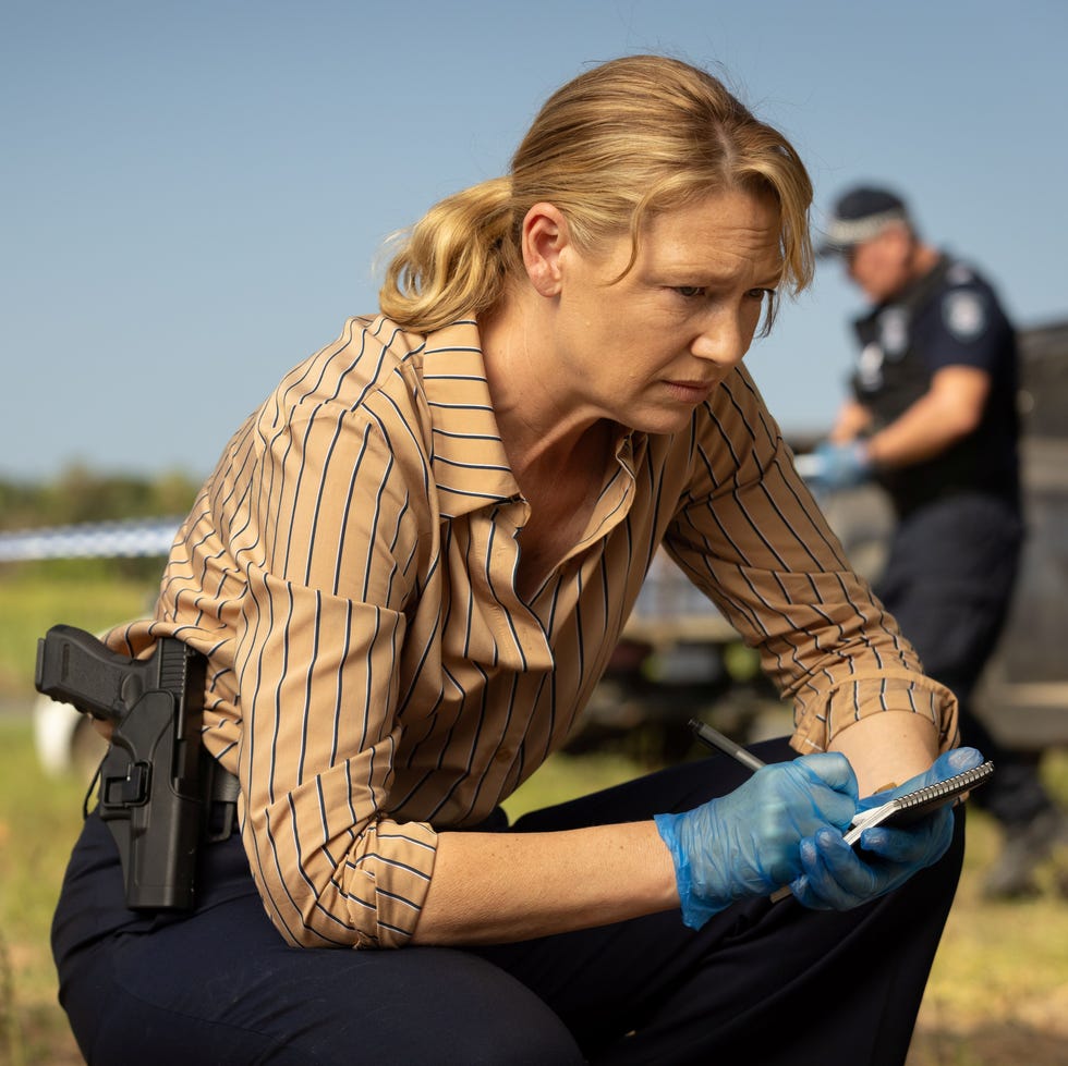 detective taking notes at a crime scene with another officer in background detective taking notes at a crime scene with another officer in background