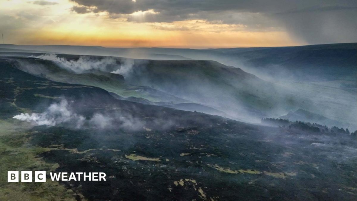 Smoke rises from a large area of scorched ground following a wildfire in Glossop, Derbyshire on June 25