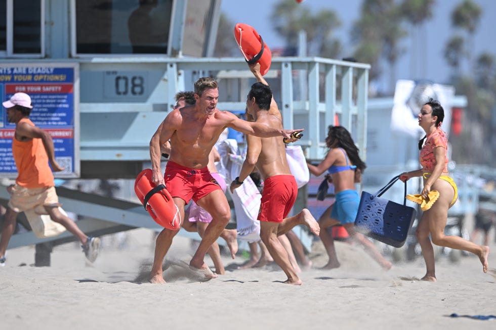 Stephen Amell filming Baywatch in Los Angeles stephen amell runs shirtless on the beach with a red bouyancy aid while filming baywatch in los angeles