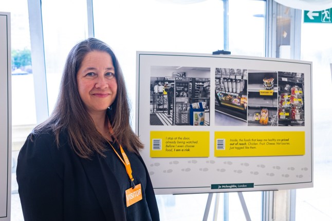 Jo at Parliament with her photo poem. She has dark hair and looks directly at the camera and smiles.