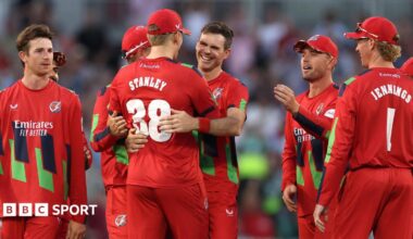 Jimmy Anderson (centre) is hugged by Mitch Stanley (STANLEY 38) with other Lancashire fielders around them after getting the wicket of Joe Root