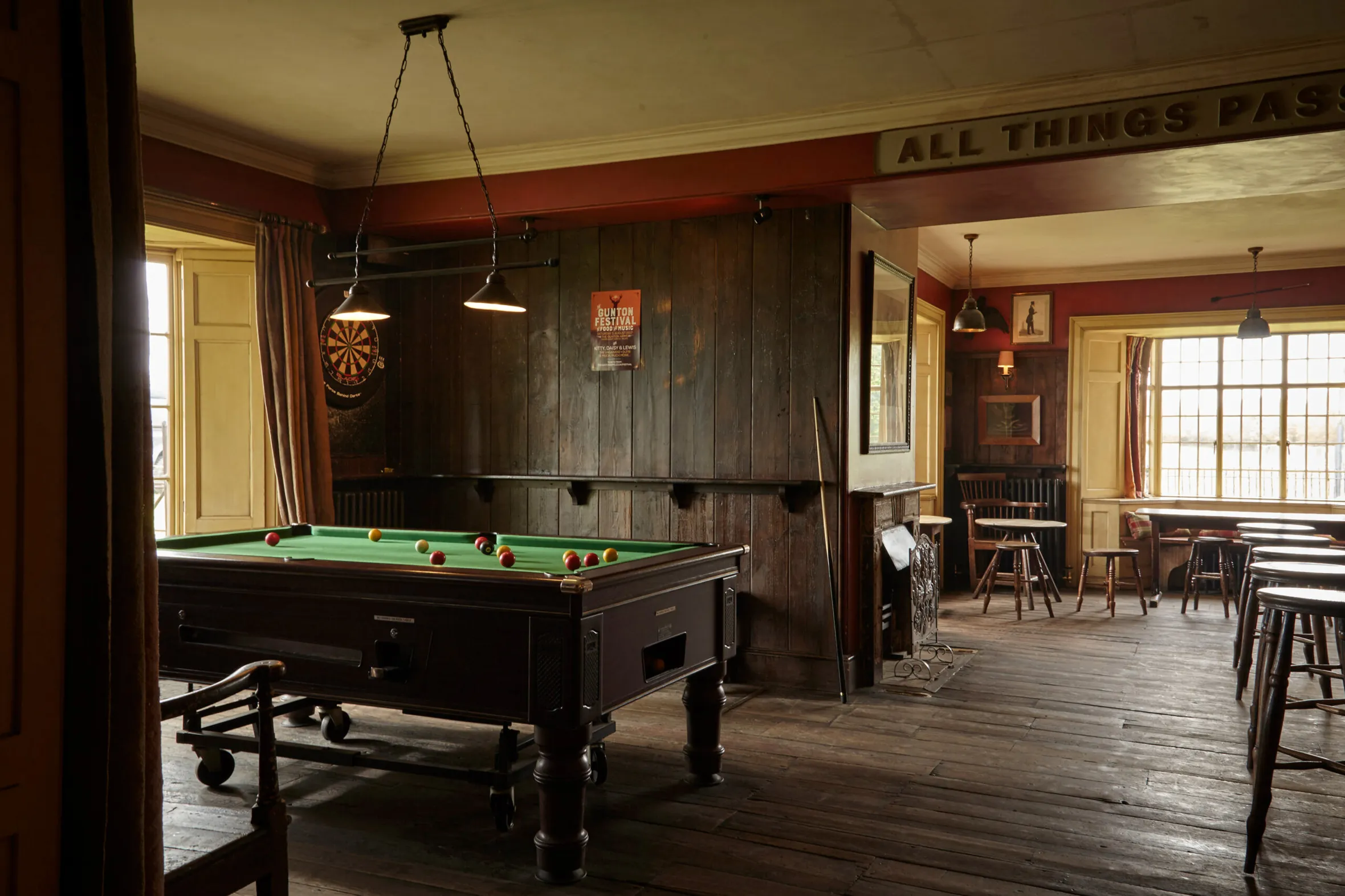 The interior of the Gunton Arms bar with a pool table, dartboard, and seating areas.