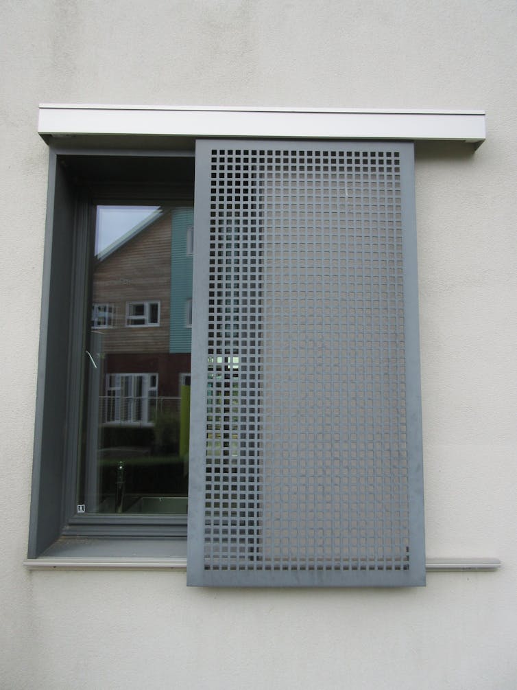 A window with a grey grille in front.
