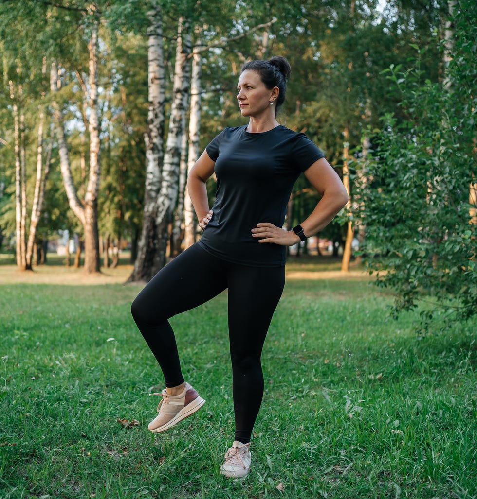 woman on warm-up doing stretching in the park outdoor woman warming up in training, outdoor fitness, stretching exercises