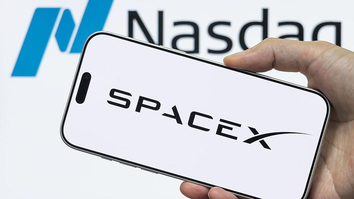 A phone with the SpaceX logo is being held up in front of a background with the Nasdaq logo.