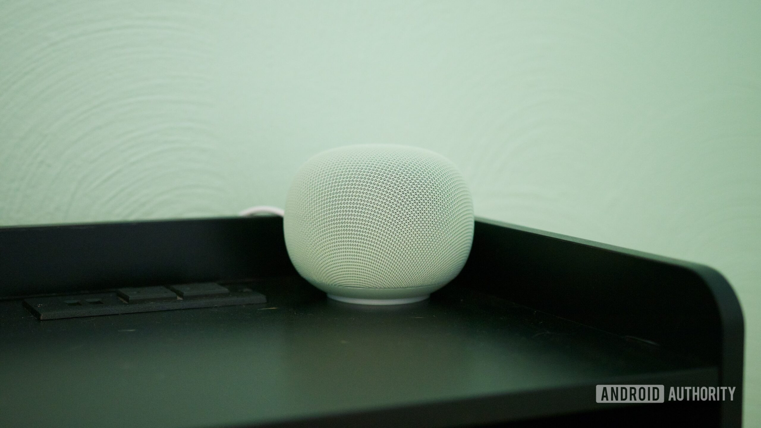 google home speaker review 1 The Google Home Speaker sitting on a black nightstand.