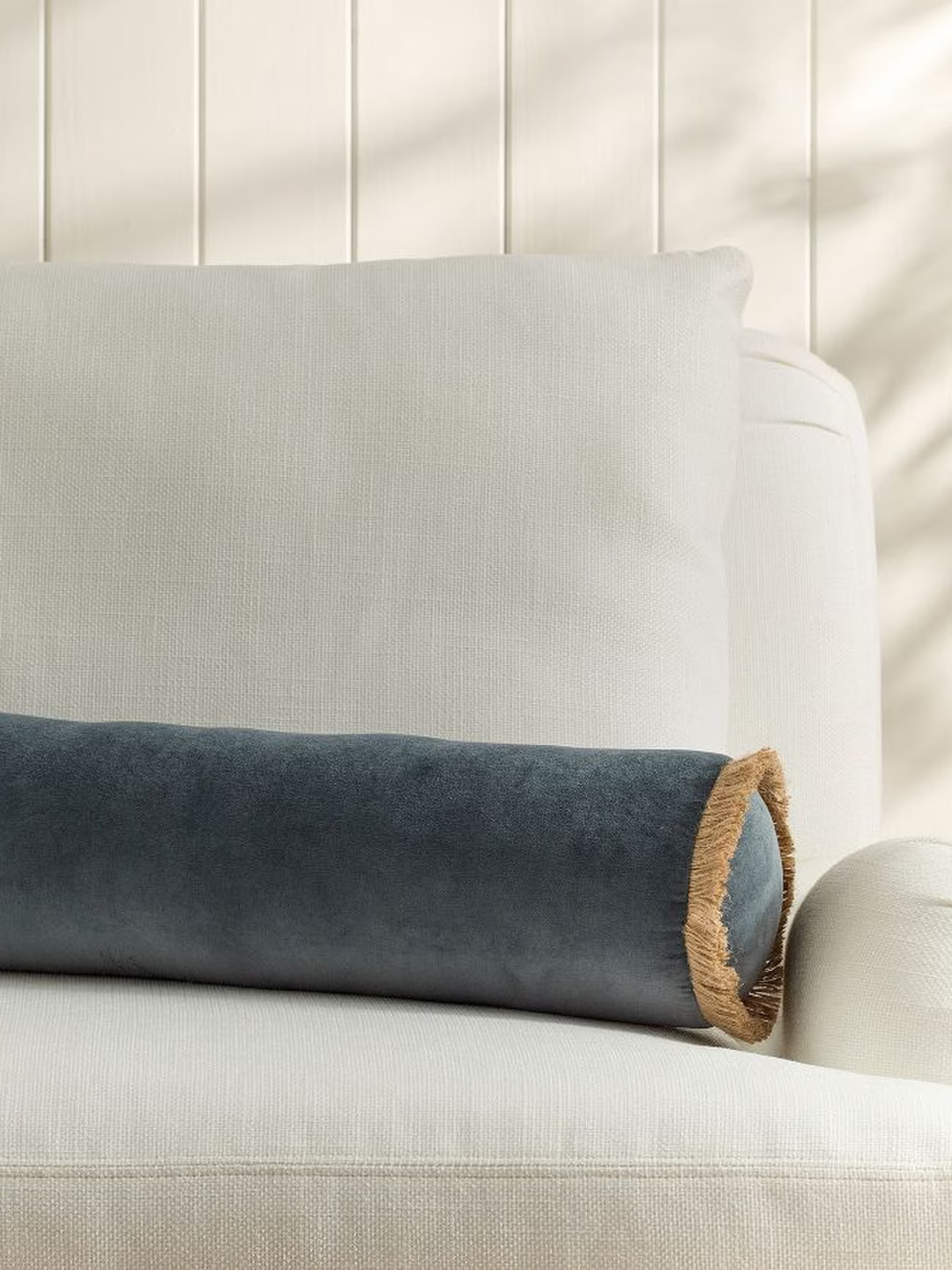 A velvet blue bolster pillow with fringe from Pottery Barn