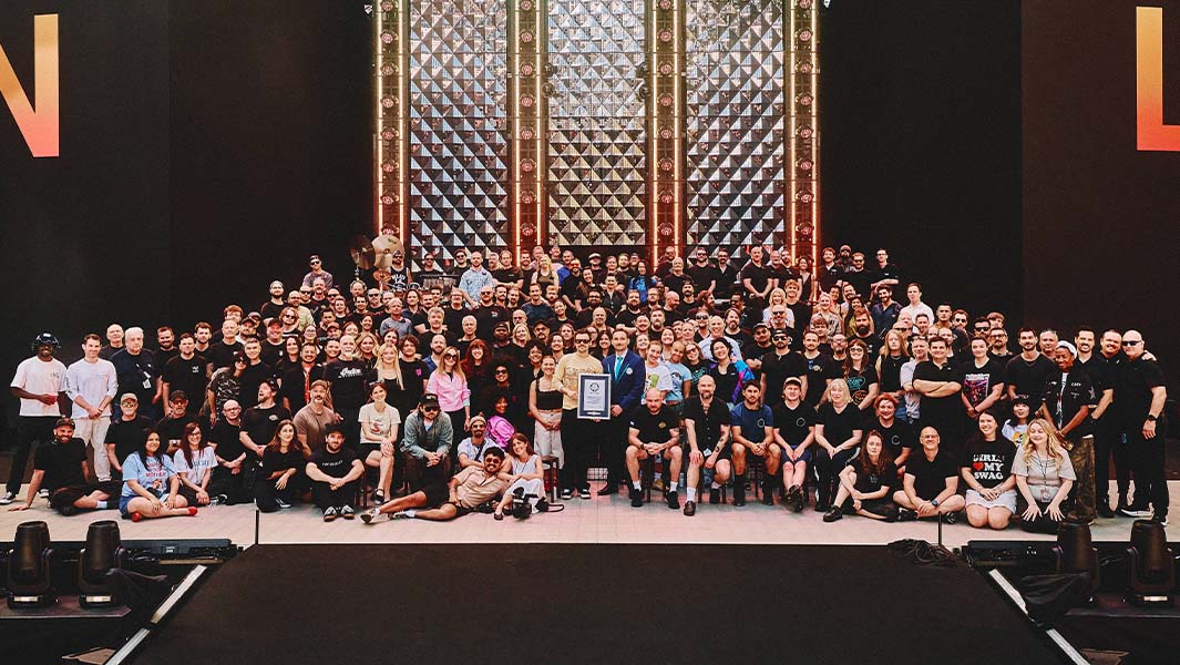 Harry Styles on stage surrounded by his tour crew being presented a GWR certificate
