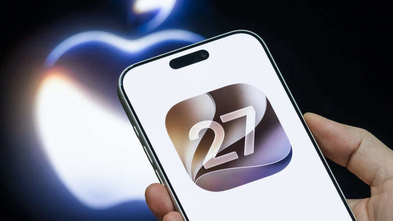 The iOS 27 logo seen on an iPhone, with the Apple logo in the background.