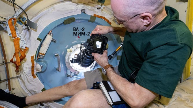 Dec. 7, 2024) --- NASA astronaut and Expedition 72 Flight Engineer Don Pettit points a camera outside a window on the International Space Station's Poisk module for a sun photography session.