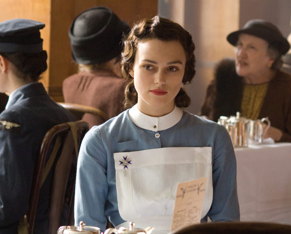 Keira Knightley as Cecilia Tallis, Atonement keira knightley as cecilia tallis in a blue dress with a white apron seated at a table in a dining setting in movie atonement