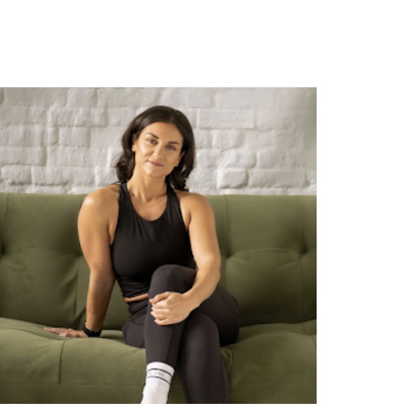 woman in fitness kit poses on green sofa