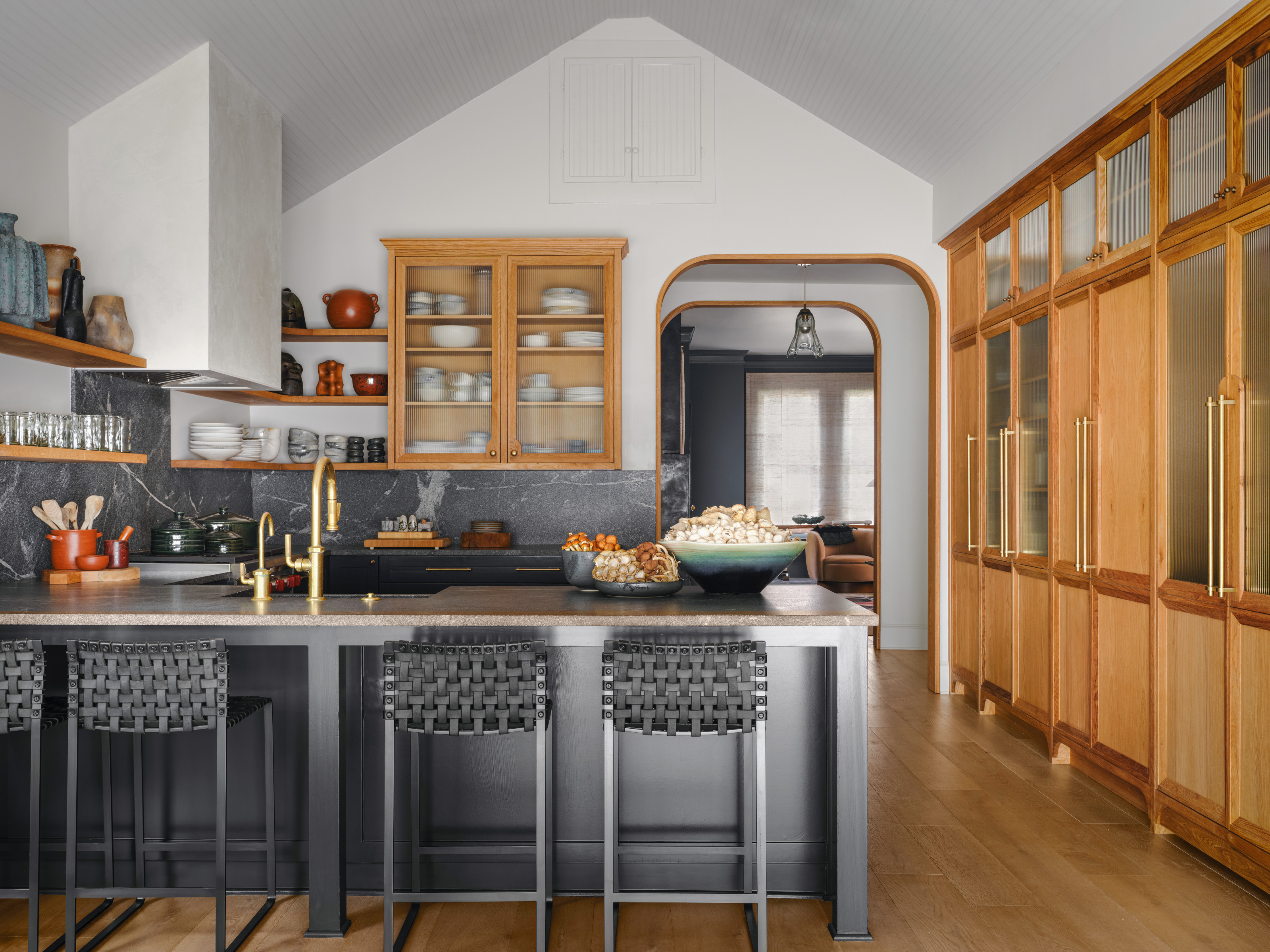 Grey metal kitchen with L-shaped island, grey bar stools, oak built-in storage and wood floor