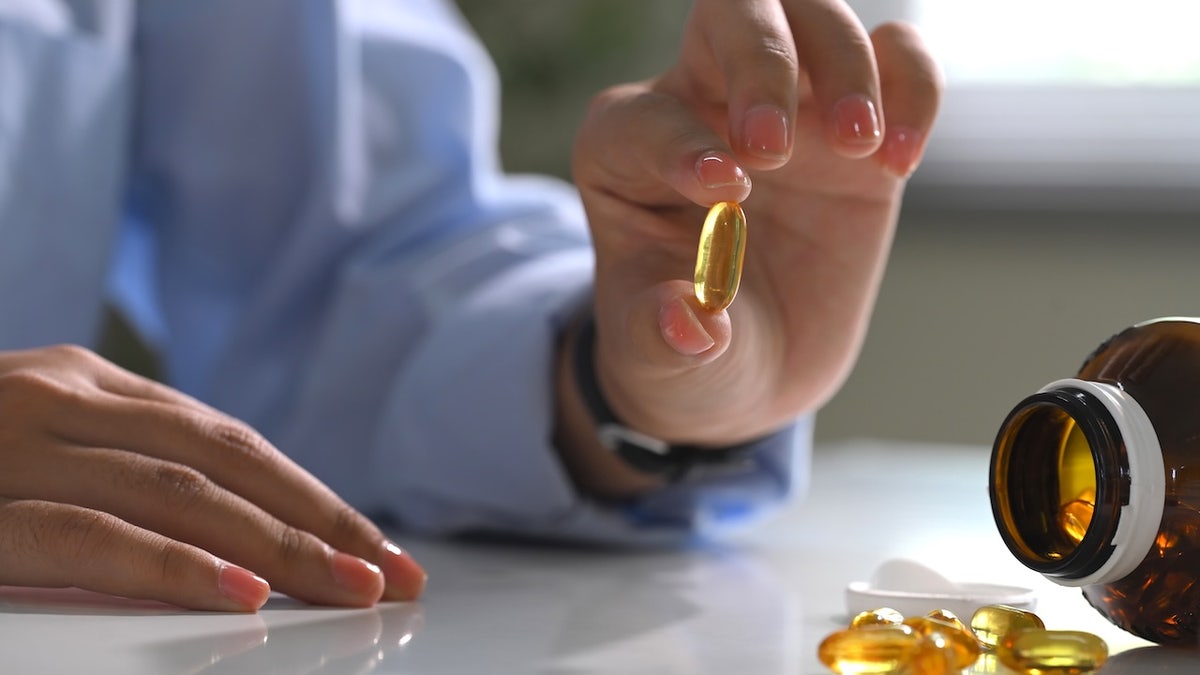 Hand holding a softgel fish oil capsule