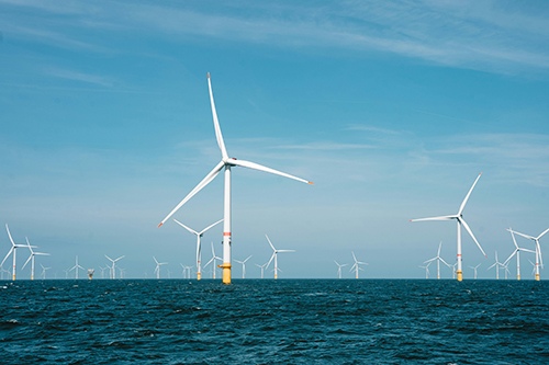 Multiple white wind turbines in the sea with clear blue skies