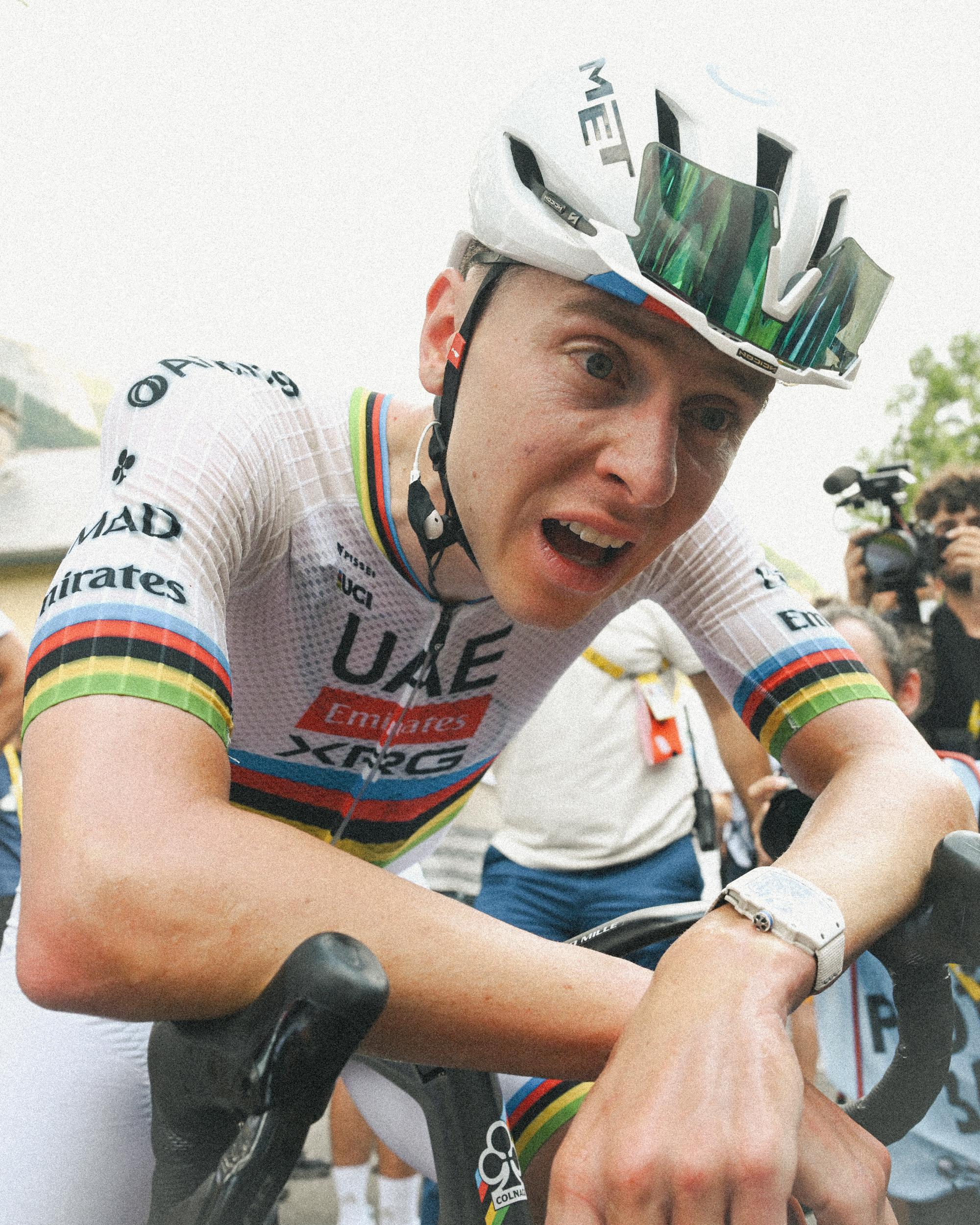 Tadej Pogačar hunches over his handlebars looking exhausted by heat
