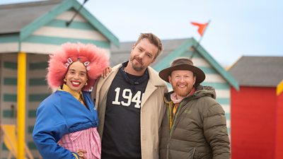 Sadie Clayton, Iain Stirling and Jamie Wardley standing outside some brightly coloured beach huts