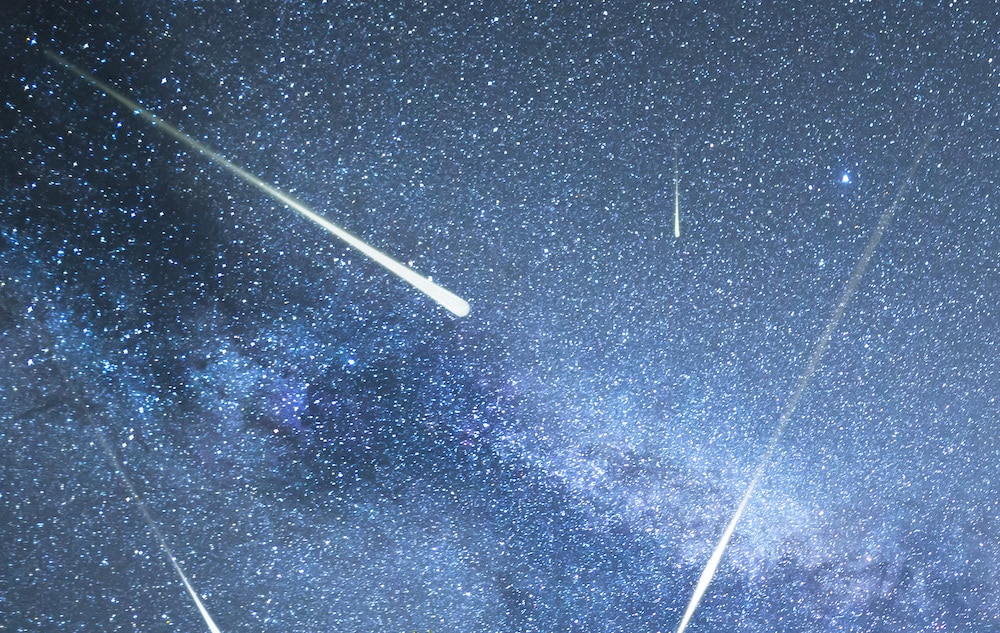 a starry night sky with meteors streaking across it