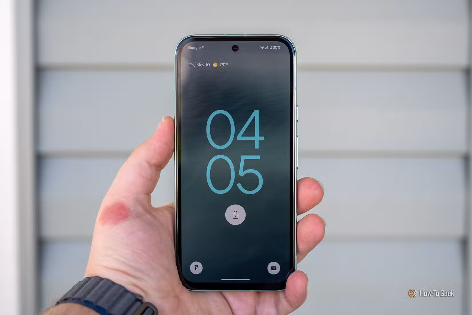 Person holding the Google Pixel 8a showing the lock screen