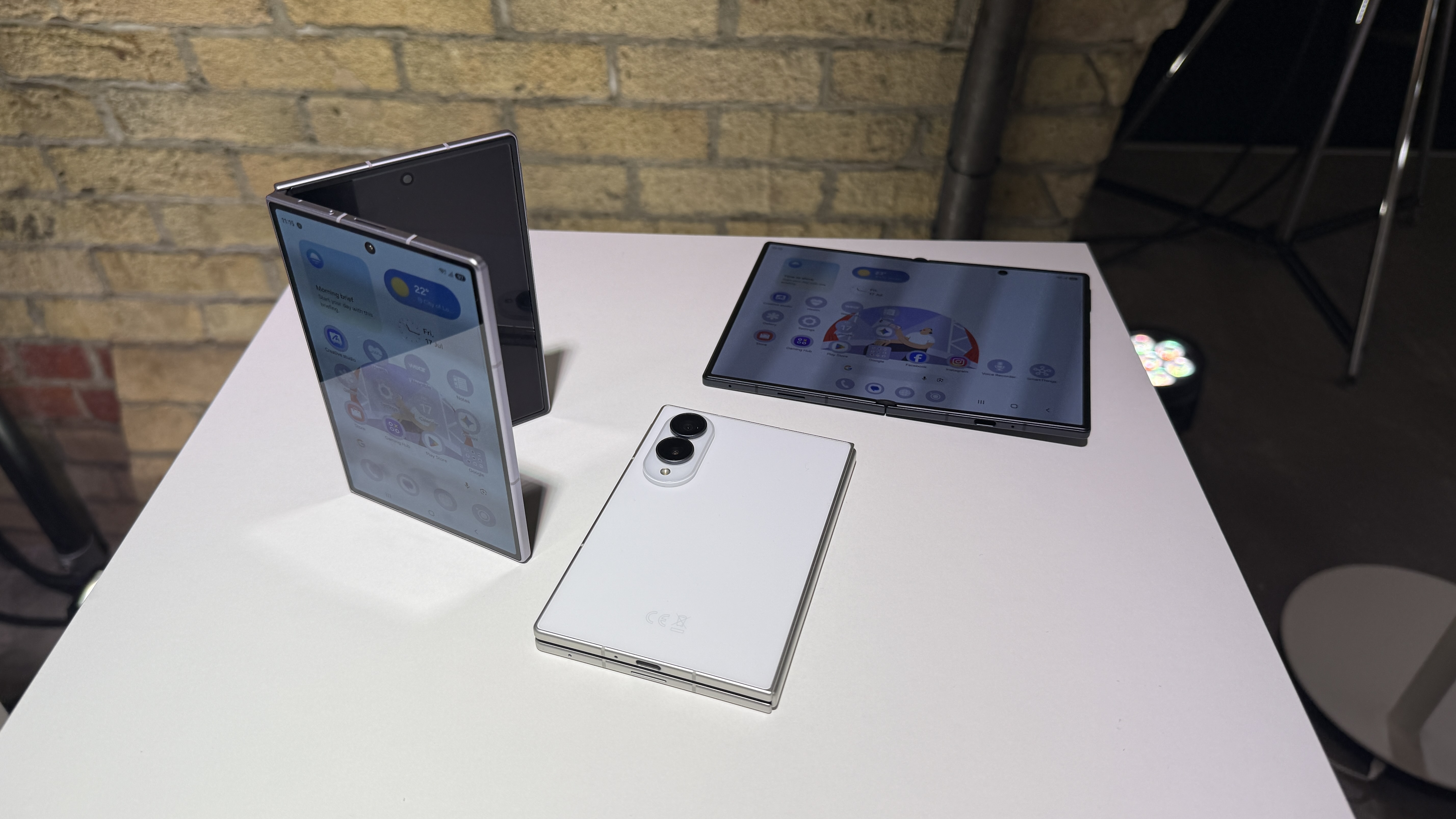 Samsung Galaxy Z Fold 8 and 8 Ultra in hand at a hands on event with a brick wall in the background