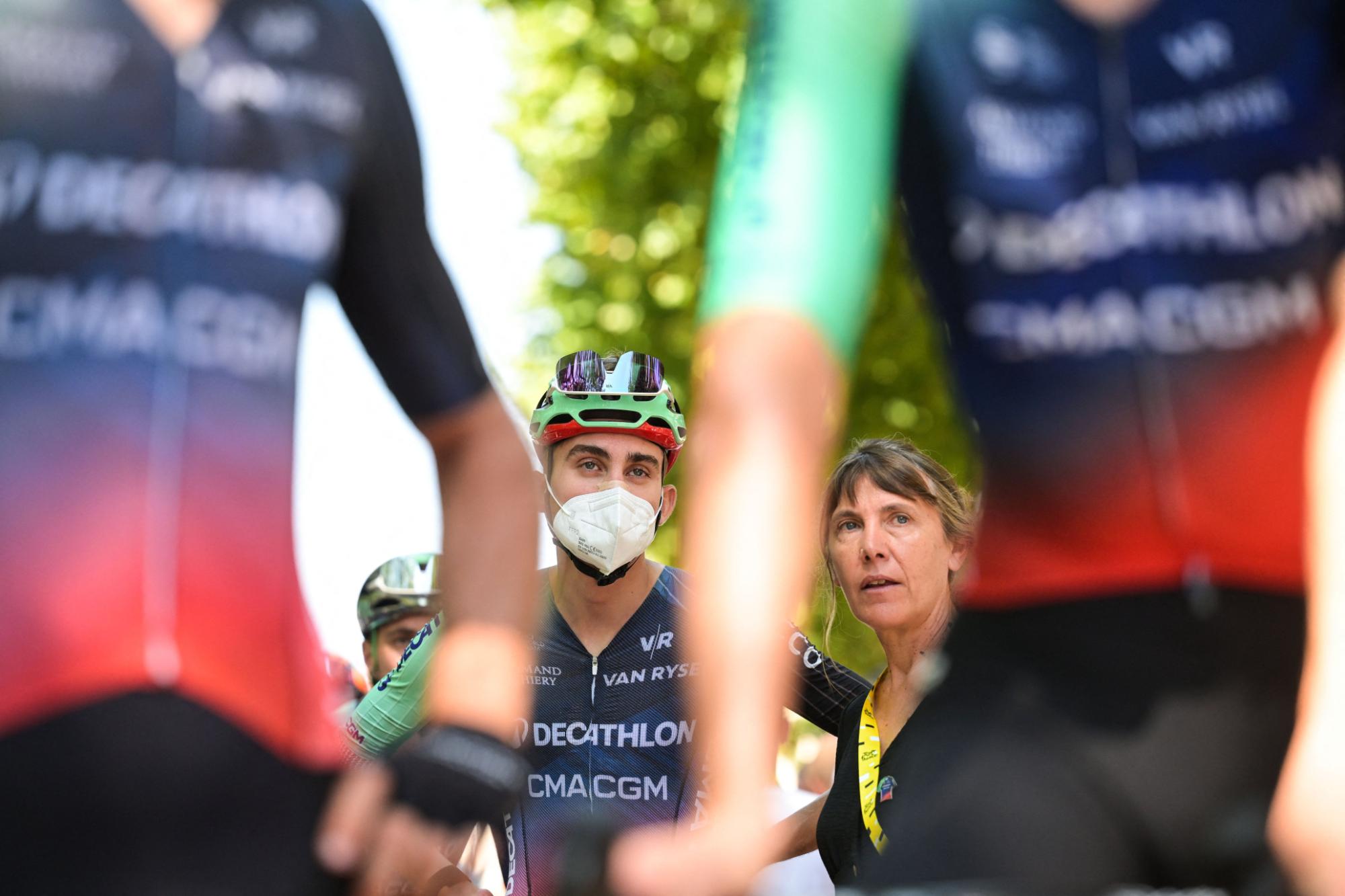 Surrounded by teammates, Paul Seixas wears an N95 mask