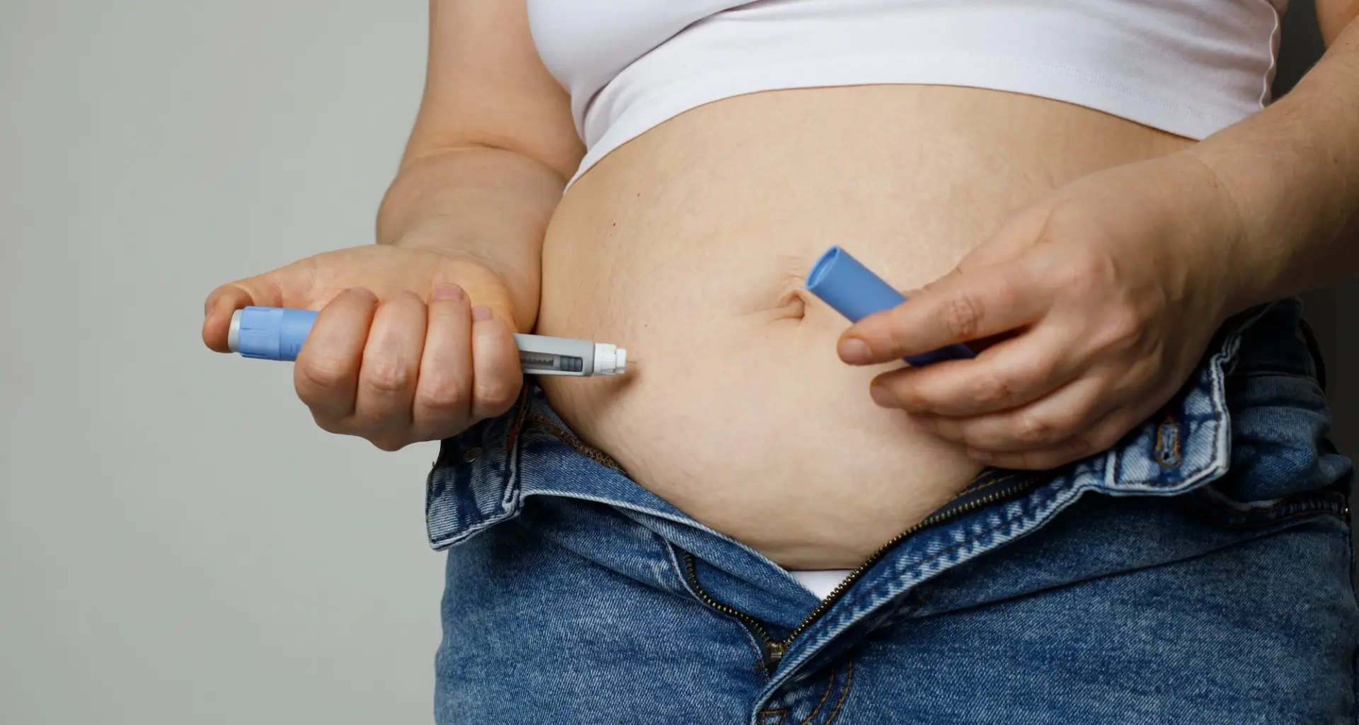 woman injects herself with a GLP-1 drug