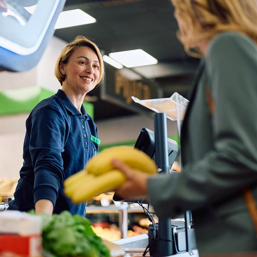 woman interacting with smiling grocery store cashier communicating with a stranger