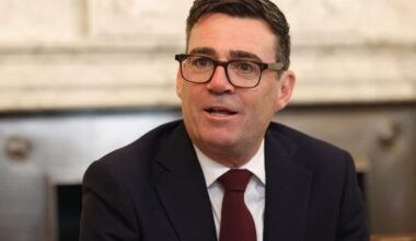 Andy Burnham wearing glasses and a suit.