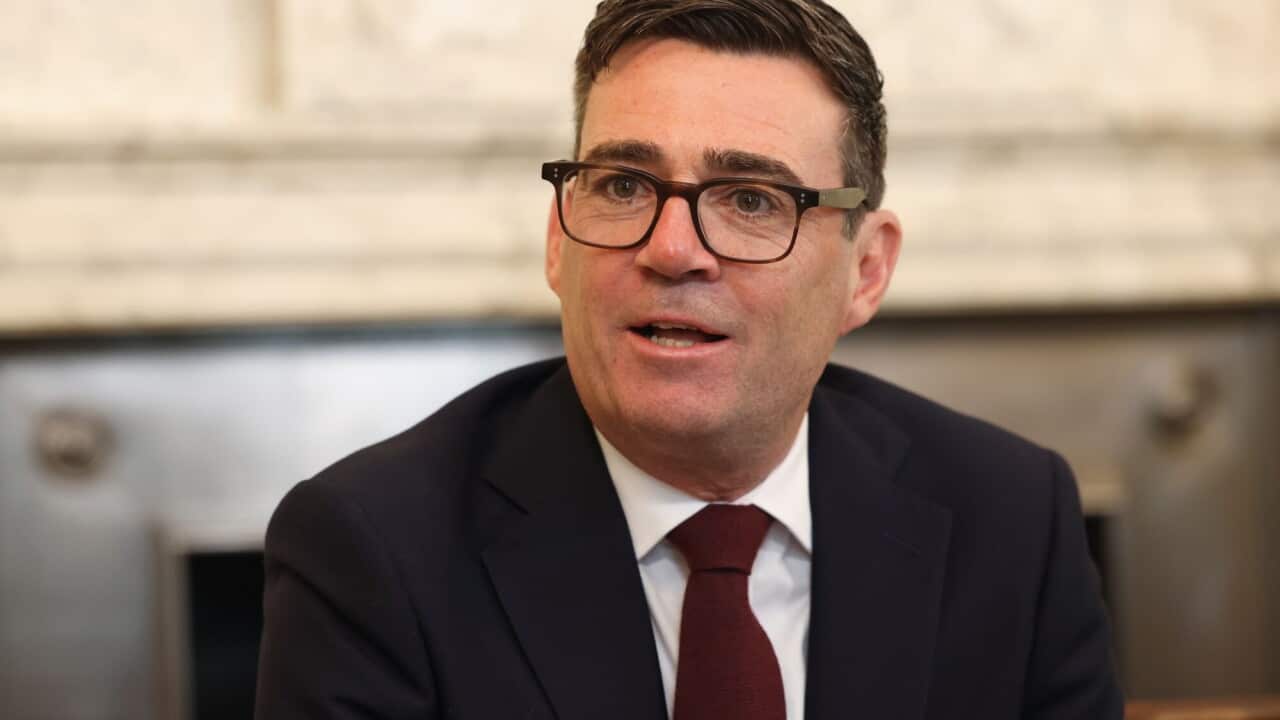 Andy Burnham wearing glasses and a suit.