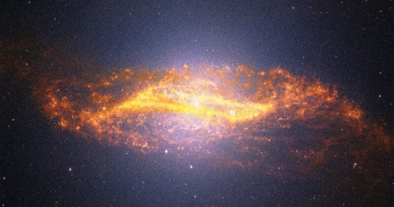 A bright, glowing spiral galaxy with fiery orange and yellow dust swirling around its center, set against a dark, star-filled space background.