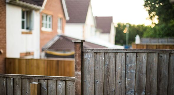 Wooden garden fence with houses defocused in back Wooden garden fence with houses defocused in back
