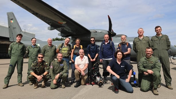 A team of scientists standing in front of plane