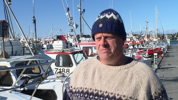 Gulli Jonasson standing on a dock beside boats speaking to RTÉ News