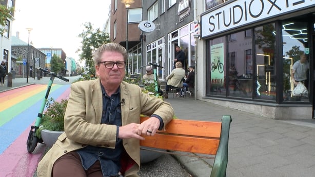 this photo shows professor bergmann sitting on a bench in a street