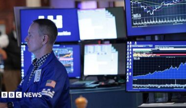 A stock market trader monitors screens on the stock market